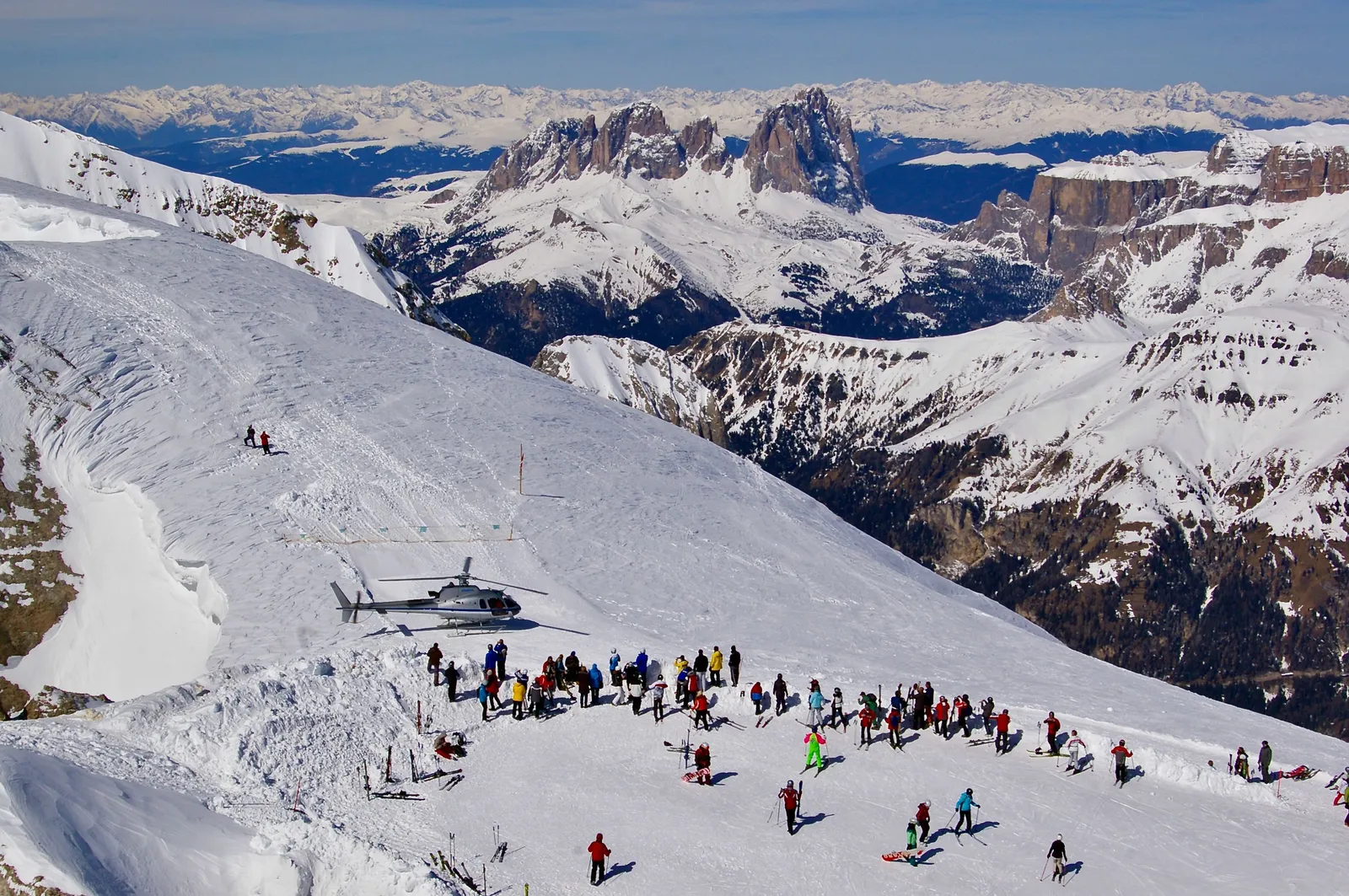 Skiers on a snow covered piste with the jagged peaks of the Dolomites behind them, Italy