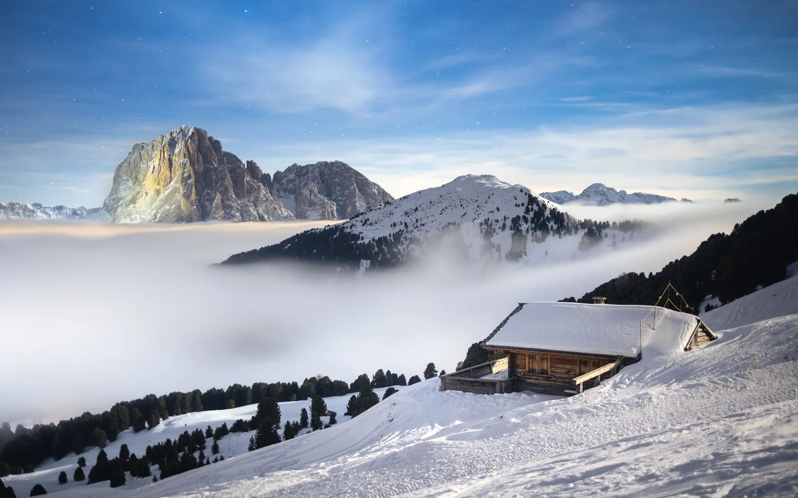 Wooden mountain hut and ski piste beneath the dramatic rock towers of the Dolomites, Italy