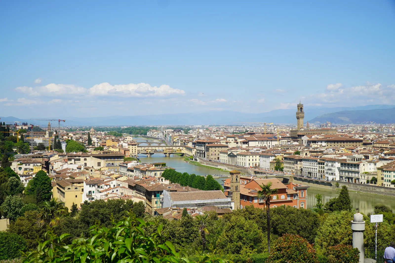 A stone bridge lined with shops crossing a river in the warm light of evening in Florence