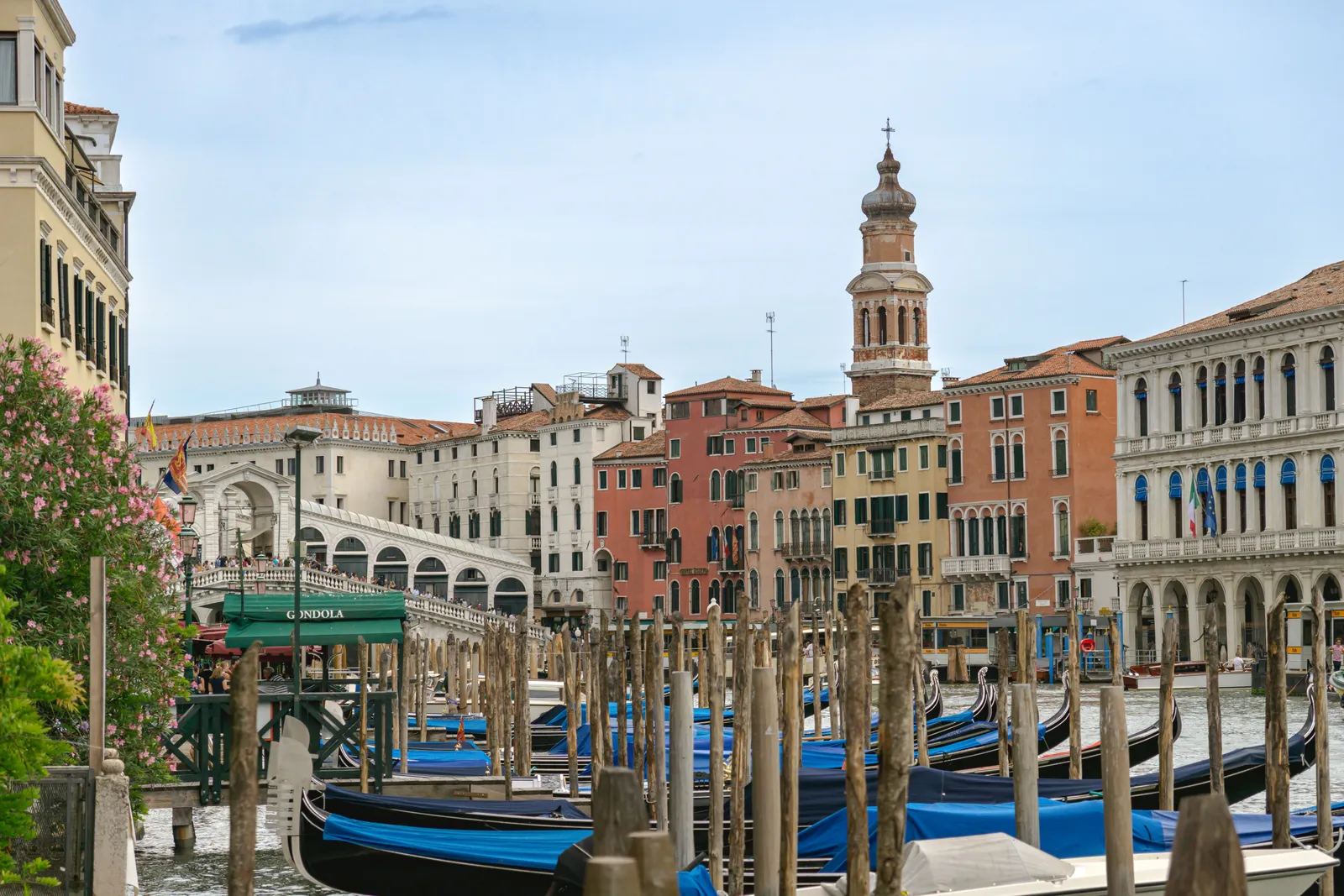 Gondolas tied up along a Venice canal with the Rialto Bridge in the background