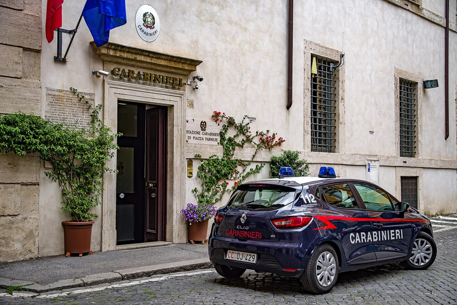 A Carabinieri police car parked outside a station entrance on a cobbled street in Rome, Italy