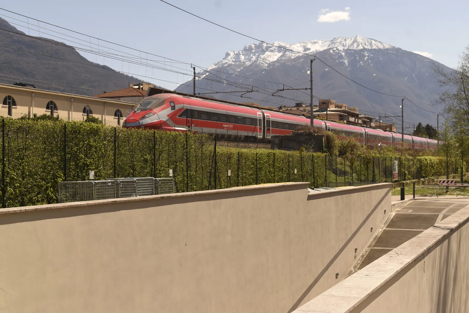 A sleek high-speed train at a modern station platform in Italy under a bright sky