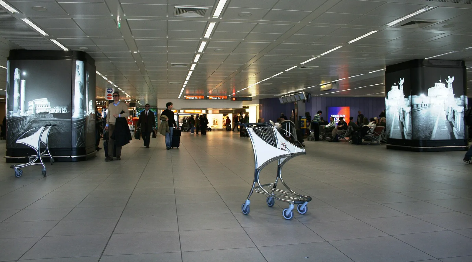Passengers with luggage carts inside the arrivals terminal at Rome Fiumicino airport in Italy