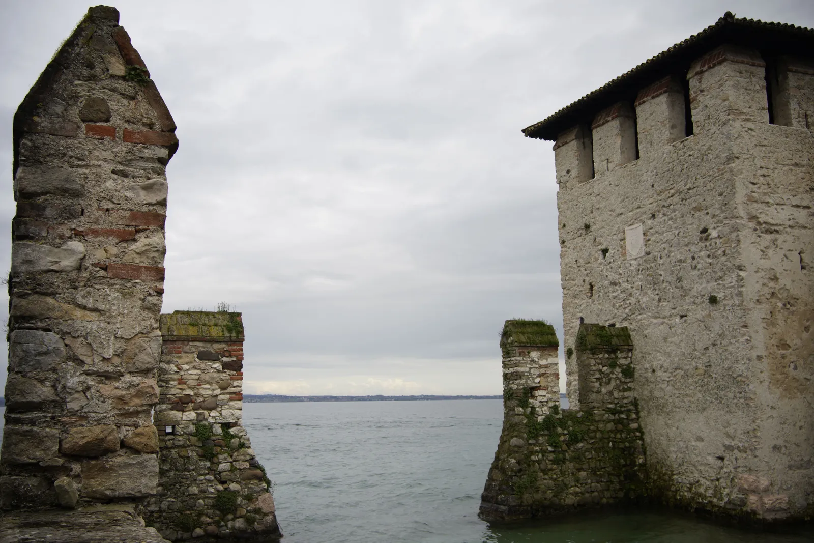 The stone walls of a castle at the water's edge on an Italian lake