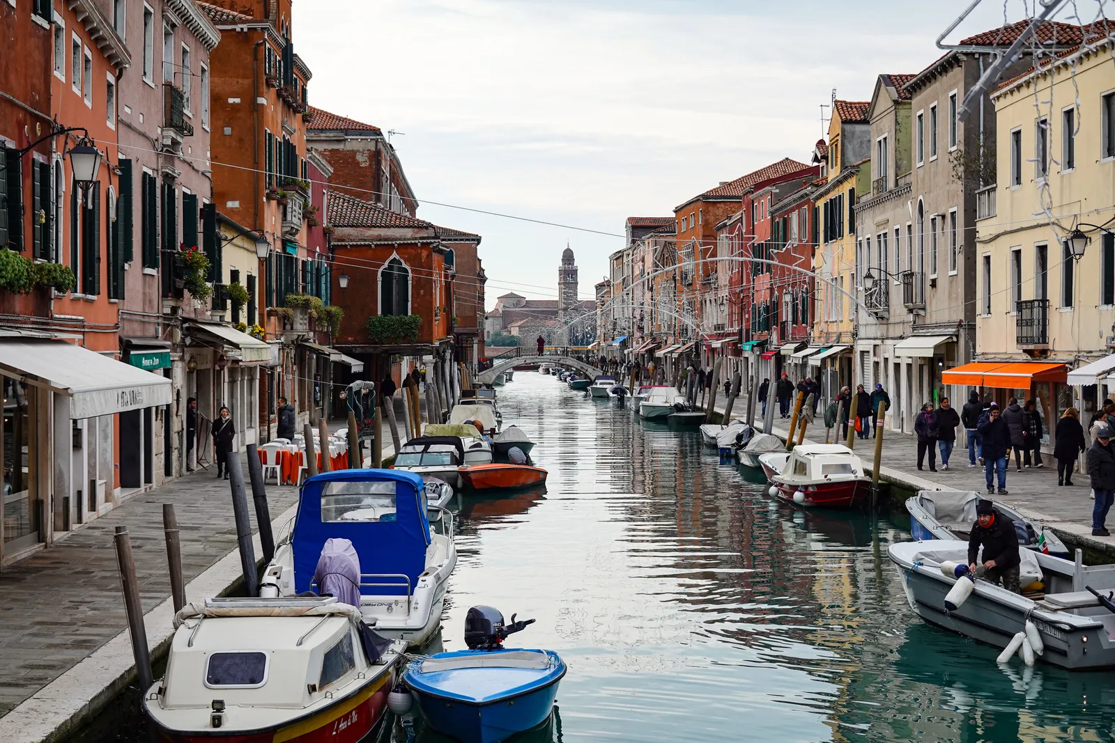A canal lined with coloured houses and small boats on Burano, Italy