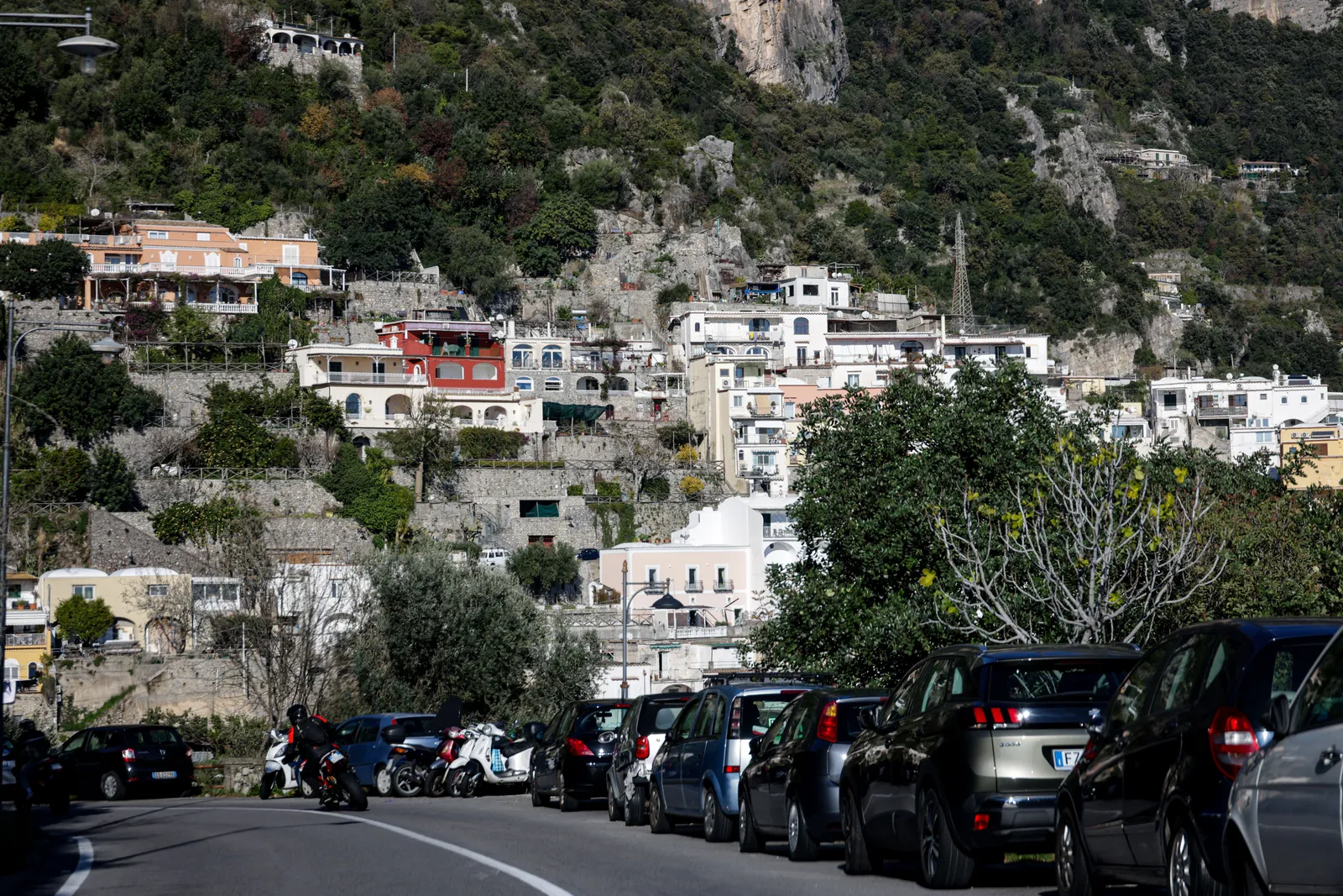 A car on a narrow cliffside bend of the Amalfi Coast road above the sea, Italy