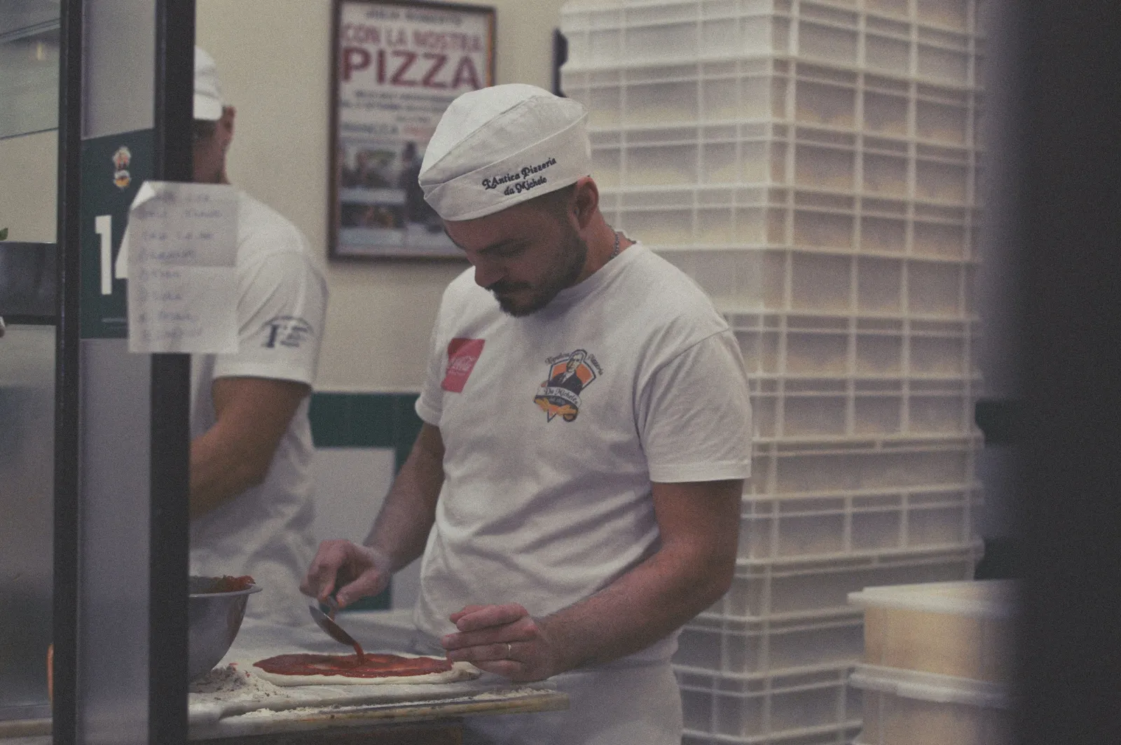 A pizzaiolo shaping a pizza base in a pizzeria in Naples, Italy