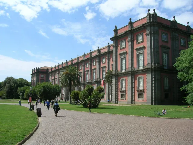 A long russet palace across a wide lawn with strollers