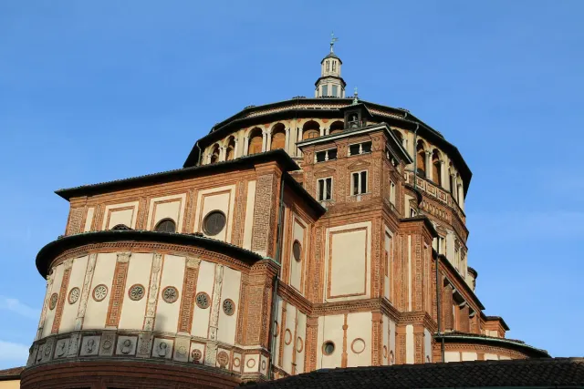 A red brick building with a dome and decorated gables in daylight
