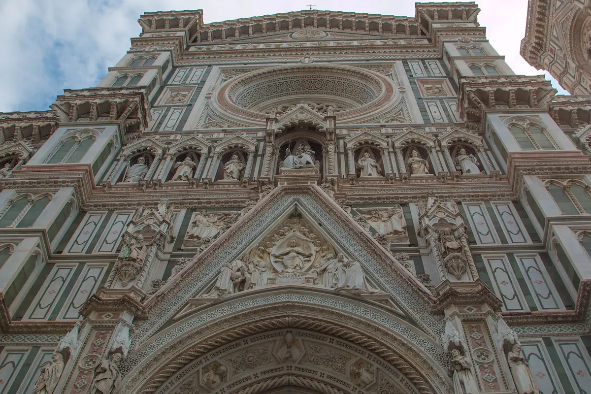 Marble facade banded in green, pink and white with statue niches and a carved gable