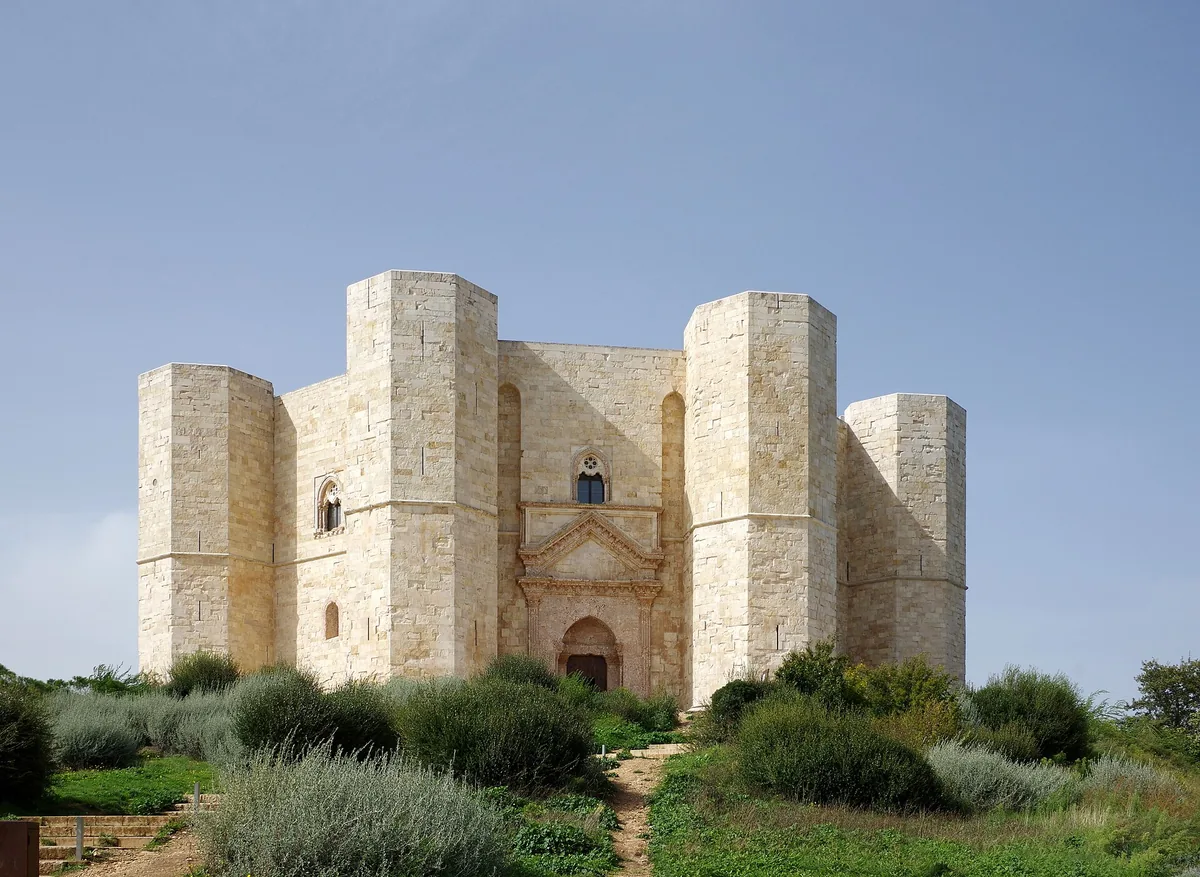 An octagonal stone fortress with corner towers on a scrub covered hill