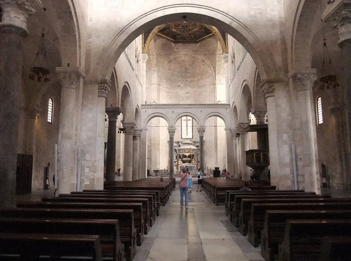 Romanesque nave with stone piers, arches and wooden pews along the aisle