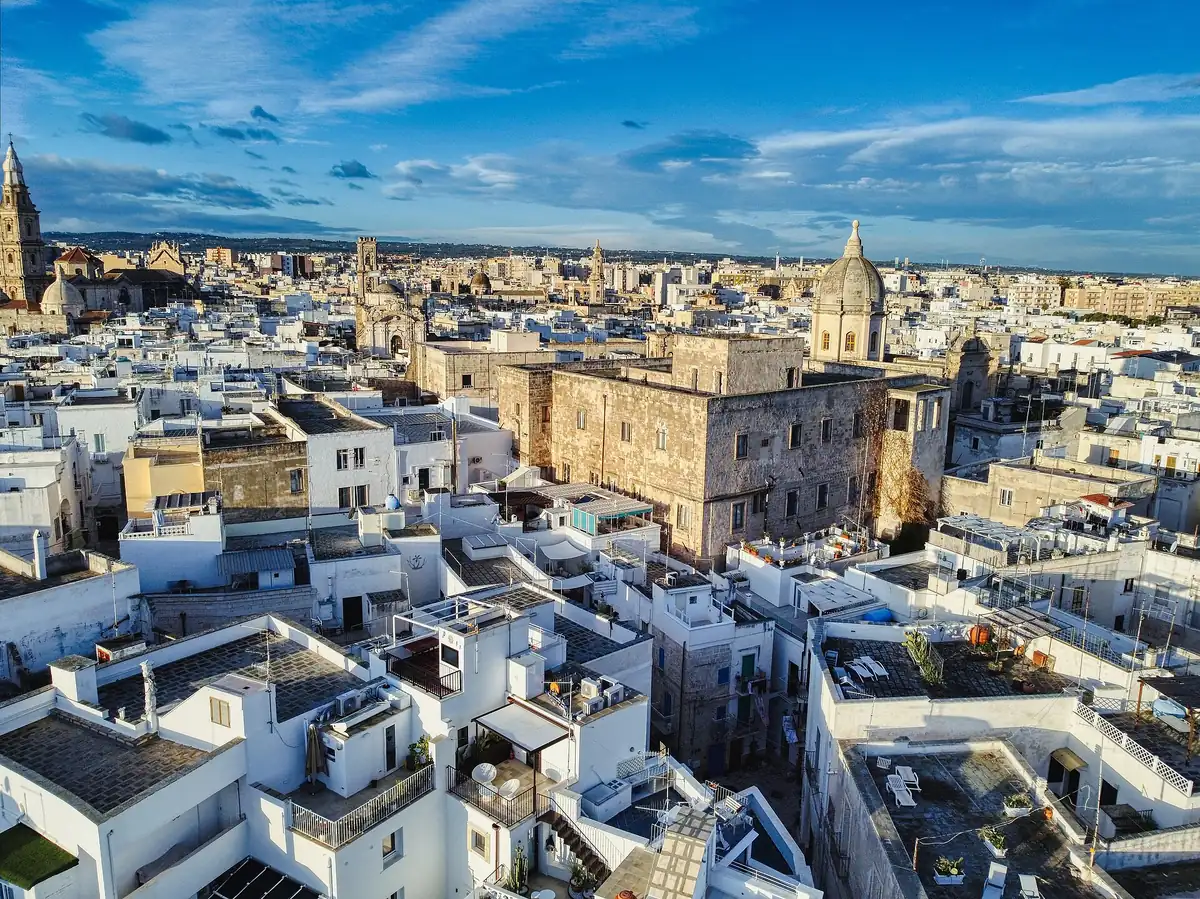 Whitewashed old town rooftops sloping toward the sea under a blue sky