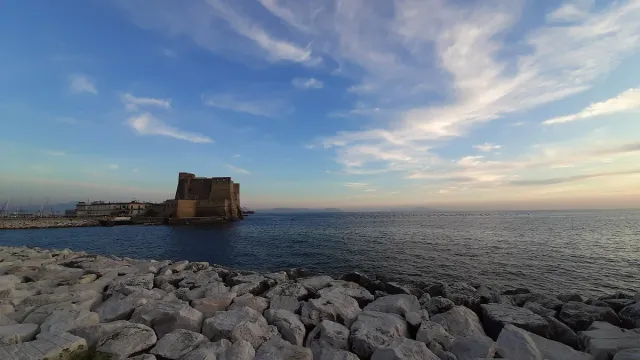 A pale stone fortress on a rocky breakwater facing the sea