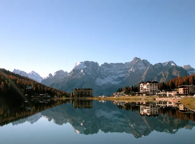 A still mountain lake reflecting snowy peaks and lakeside houses