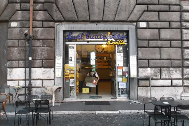 A small cafe front on a stone street with metal tables outside