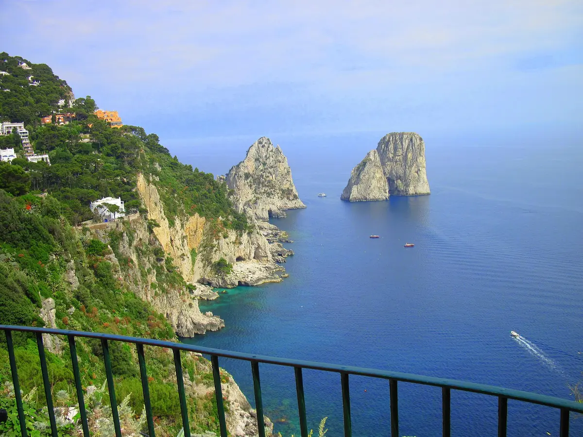 View over a railing to white rock stacks rising from a deep blue sea