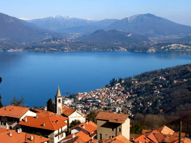 A town of tiled roofs on the shore of a broad lake ringed by mountains