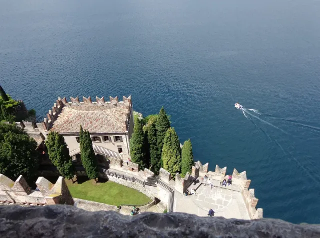 A castle with a square tower on a cliff above blue water