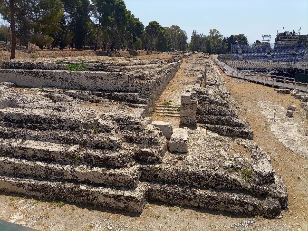 Carved stone rows of an exposed ancient structure with green trees on the horizon on a sunny day