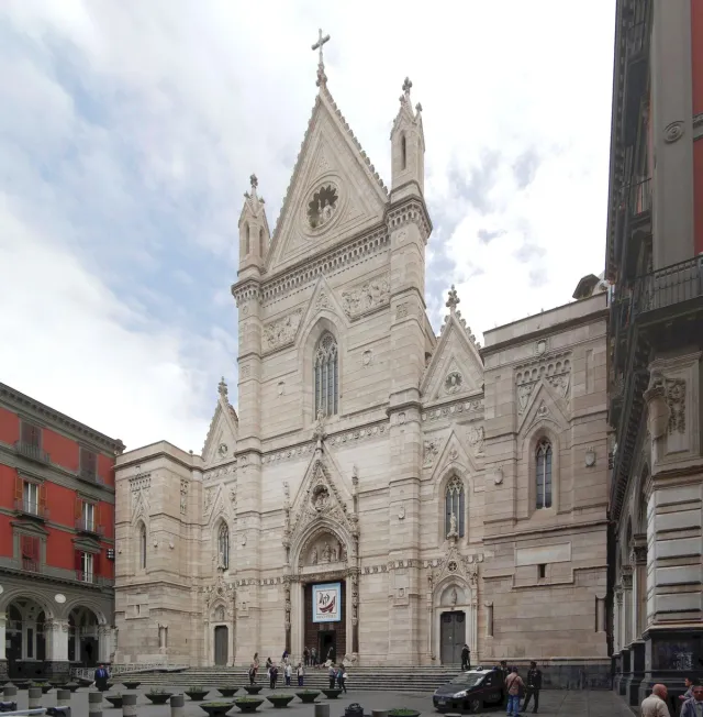 A pale Gothic facade with three pointed portals above a flight of steps