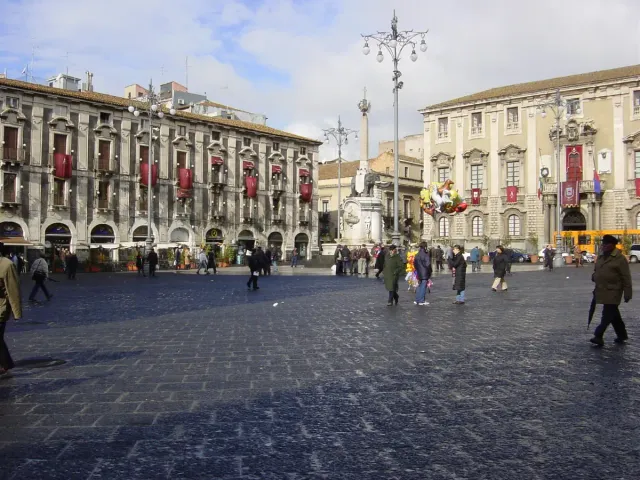 A paved square with a baroque cathedral and visitors in daylight
