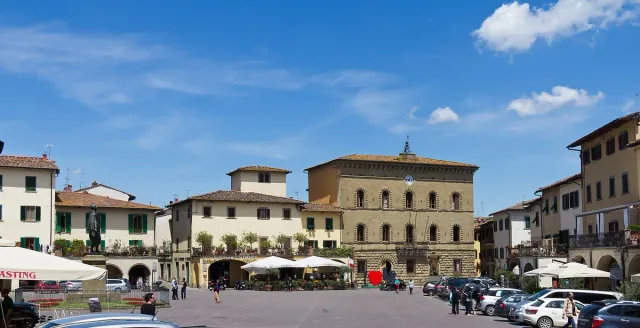 A triangular square with arcades, balconies and cafe awnings in a Tuscan town