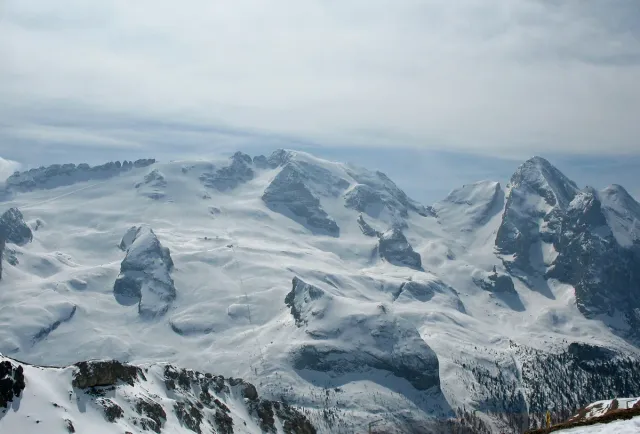 A broad snow covered glacier ridge under a pale sky