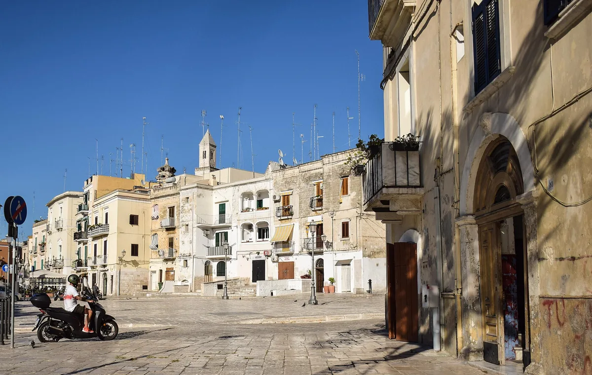 A stone paved square in an old town with pale stone houses and a bell tower