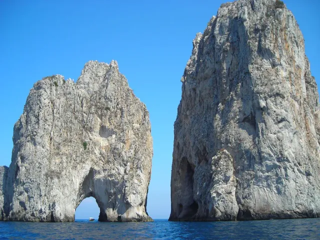Two huge rock stacks with a natural arch rising from blue sea