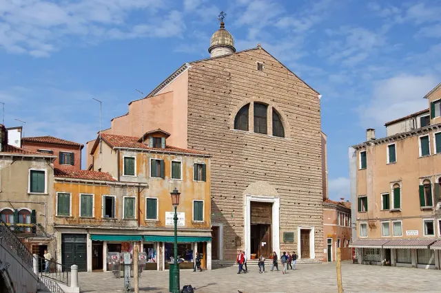 A bare brick church front at the end of a small square lined with shops