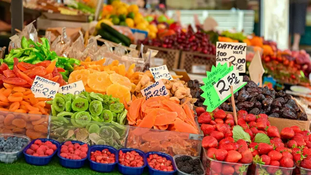 A market stall piled with colourful fruit and vegetables and price signs