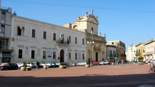 A paved town square with pale buildings and palm trees
