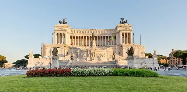 A huge white marble monument with colonnade and steps above gardens