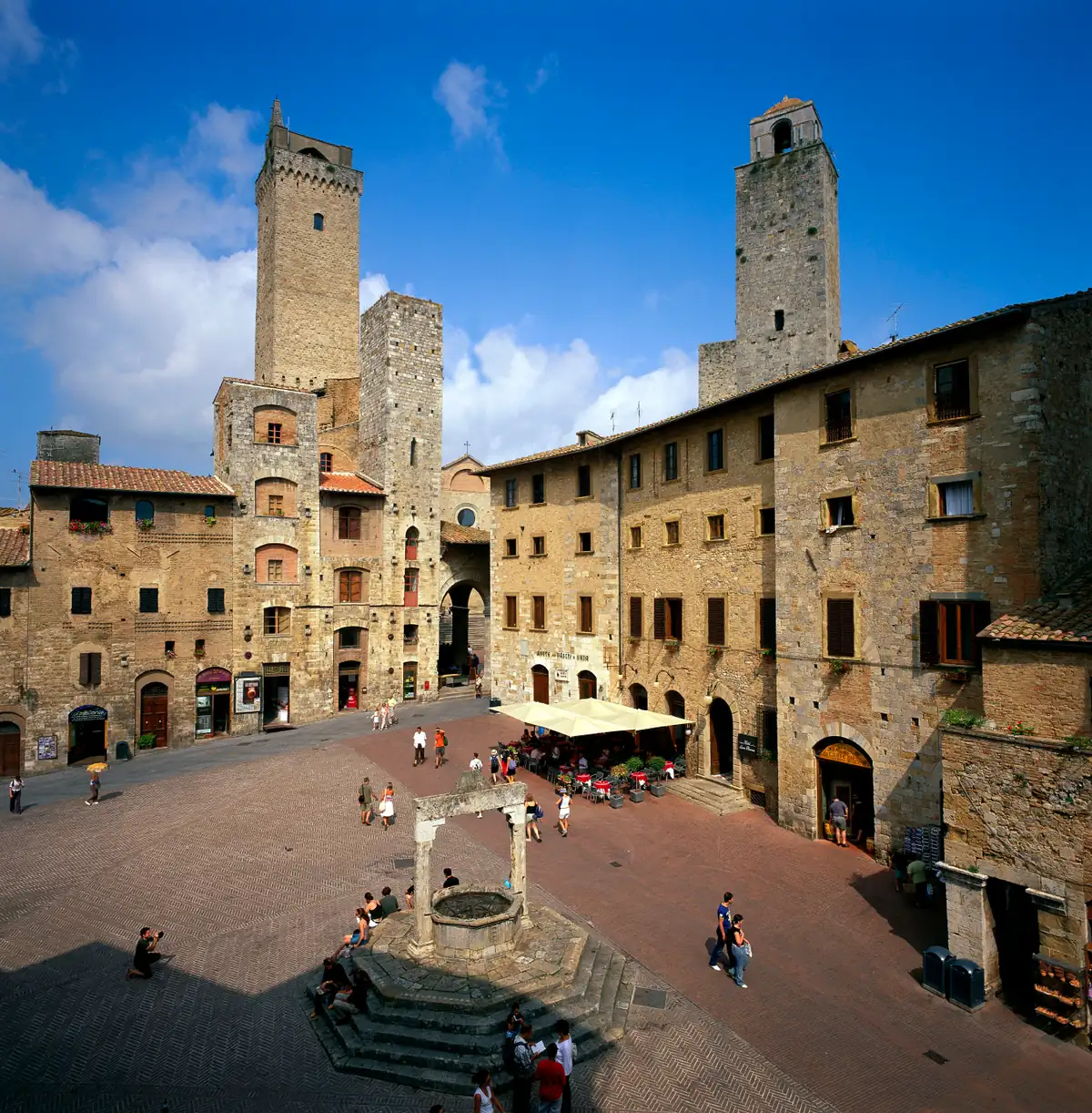 A medieval square ringed by stone houses and tall square towers
