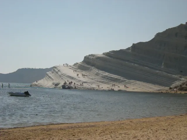 A stepped white rock slope running down to the sea and a strip of beach