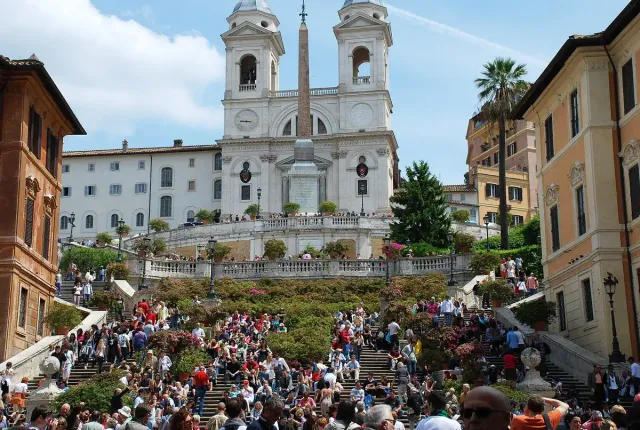 Wide stone steps crowded with people rising to a twin towered church