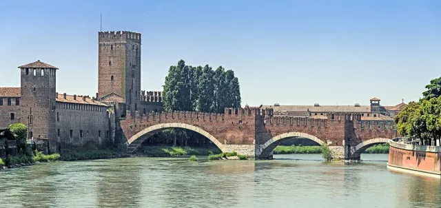 A red brick bridge with arches and battlements over a river