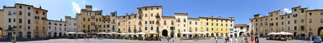An enclosed oval square of ochre houses with cafe tables
