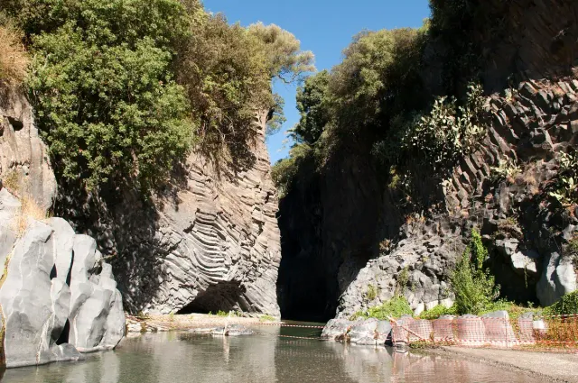 A narrow gorge between dark rock walls with shallow running water
