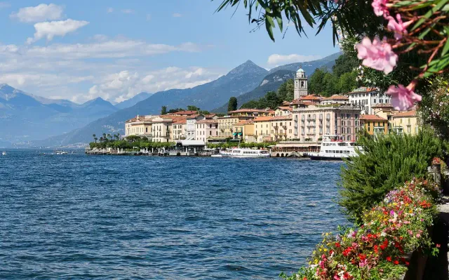 A town of ochre houses on a lake shore framed by pink blossom
