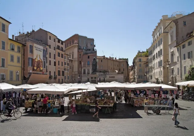 A paved square with white market stalls ringed by old houses