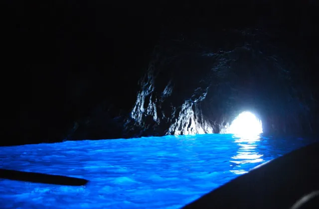 Cave water glowing intense blue in front of a bright sea opening