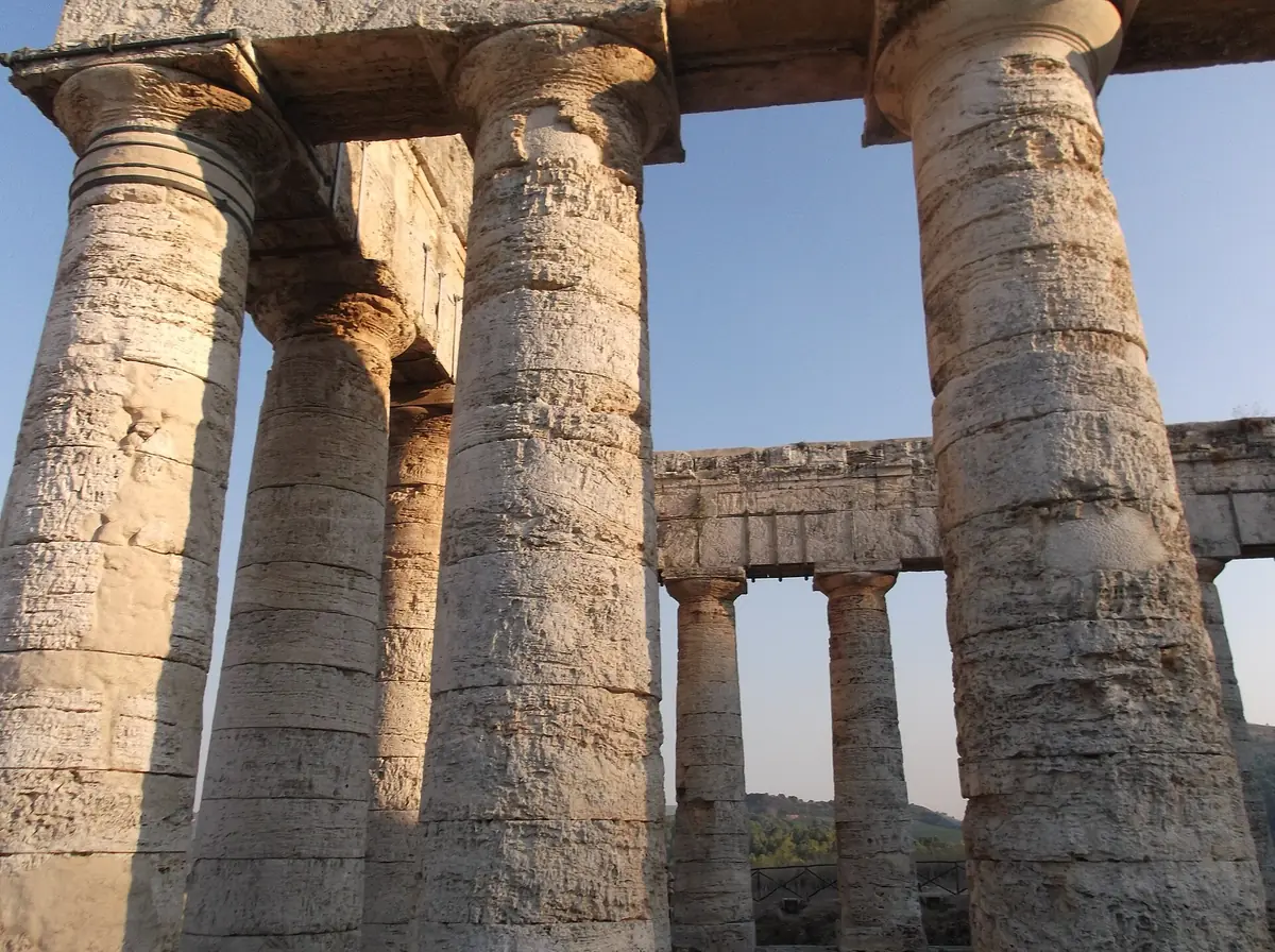 Thick Doric columns of pale stone with a further row of columns and hills seen beyond
