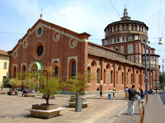 A red brick church with stone trim and trees on the square before it