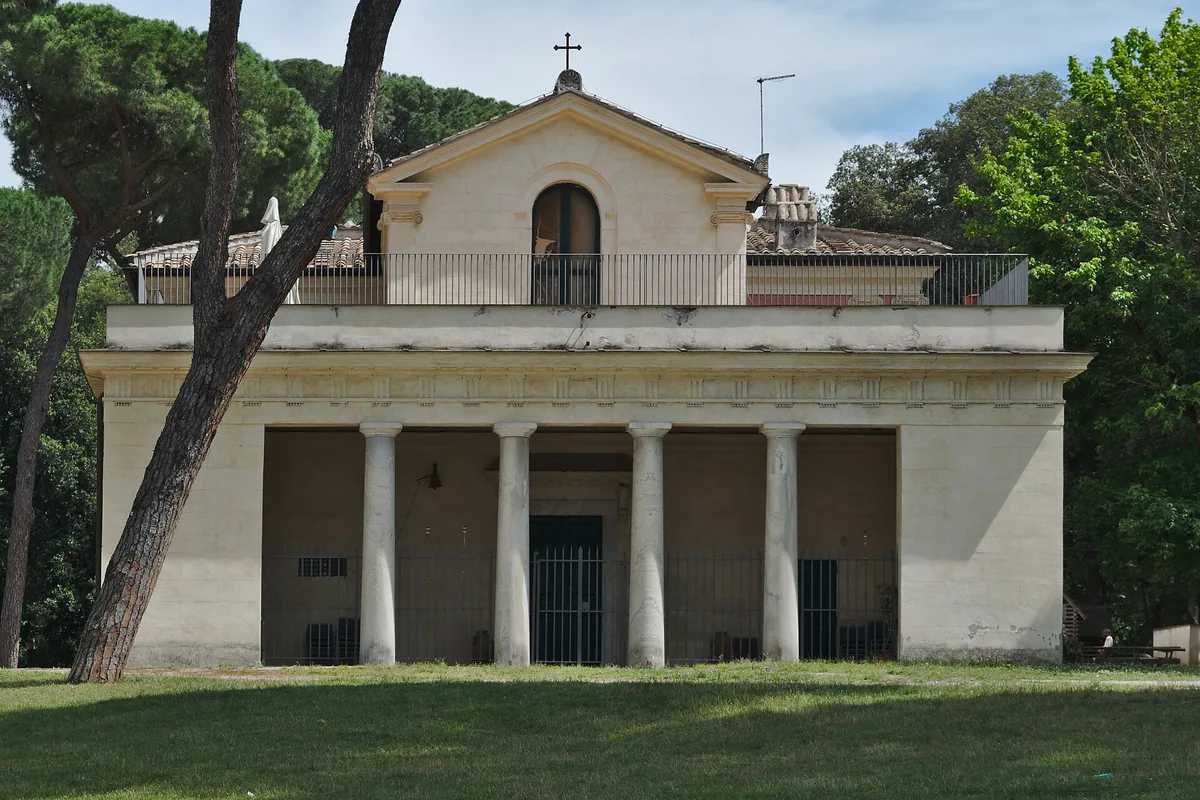 Neoclassical pavilion with columns on a green lawn among tall pines