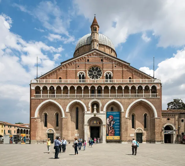 A brick facade with arches, domes and slender towers behind