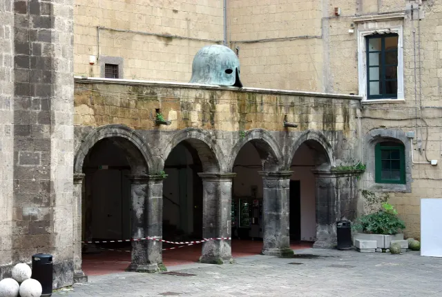 A stone castle courtyard with arcades and a two storey loggia