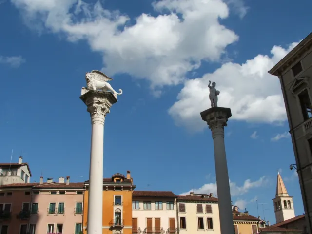 A paved square with two tall columns and an arcaded basilica