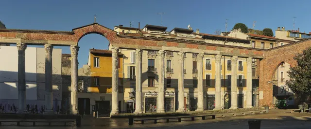 A row of ancient Roman columns standing before a church and forecourt